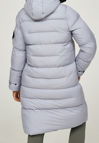 Hellgrauer Steppmantel mit horizontalen Nähten, Kapuze und schwarzen Akzenten an den Bündchen. Verfügt über ein knieumspielendes Design und eine glatte Textur.