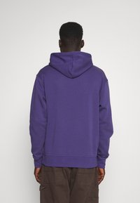 Sudadera morada hecha de material de algodón suave, con capucha con cordones, bolsillo canguro y puños y dobladillo de canalé.