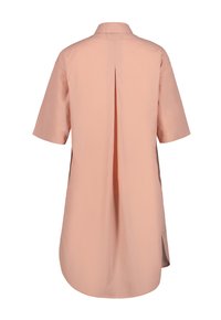 Blusa de manga corta en melocotón claro, con cuello tipo camisa, pliegue en la parte de atrás y aberturas laterales. Textura suave, corte a la altura de la rodilla.