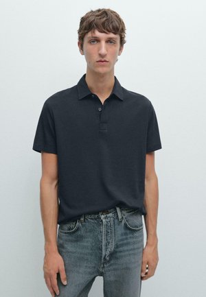 Polo shirt en coton noir avec une patte de boutonnage à trois boutons et des manches courtes, associé à un jean bleu délavé, design minimaliste, texture lisse.