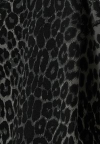 Svart tyg med ett grått leopardmönster som har varierande former och texturer, vilket ger en subtil, texturerad look.