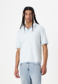 Πολυέστερ κοντομάνικο πόλο μπλουζάκι, ανοιχτό μπλε, με υφή από πλεκτό ύφασμα, διαθέτει κολάρο και μανσέτες σε αντίθεση, με σχέδιο μικρών ζιγκ-ζαγκ παντού.