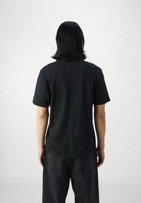 Black cotton t-shirt with a crew neck, short sleeves, and a relaxed fit. The fabric is smooth with no visible patterns or accents.