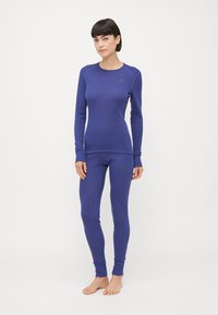 Blå langermet topp og matchende leggins i elastisk stoff. Har avrundet halslinje, figursydd design og subtil logo detaljer i gull.