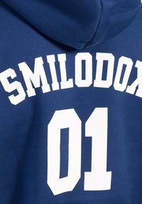 Dunkelblauer Kapuzenpullover mit weißem Blocktext, der "SMILODON" in einem Bogen über der Zahl "01" auf dem Rücken zeigt. Material aus Baumwollmischung.