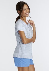 Gestreiftes T-Shirt in Hellblau und Weiß, mit V-Ausschnitt und Knopfdetail, kombiniert mit einfarbigen hellblauen Shorts. Aus weichem Baumwollstoff.