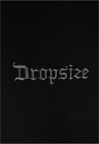 Schwarzer Stoff mit silberner, gestickter Schrift, die "Dropsize" in einer stilisierten Schriftart zeigt. Die Textur wirkt weich und gleichmäßig.