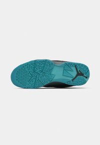 Suola della scarpa in teal e nero con motivi geometrici testurizzati e un logo Jumpman nero vicino al tallone su uno sfondo bianco.