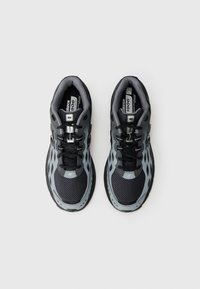 Baskets de sport grises et noires avec une tige en mesh, des accents réfléchissants et une semelle en caoutchouc robuste ; elles disposent d'un design à lacer et de détails de logo.