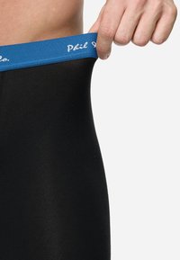 Svarta boxerkalsonger med ett blått elastiskt midjeband som har vit logotyp. Tyget ser mjukt och elastiskt ut, sitter tätt.