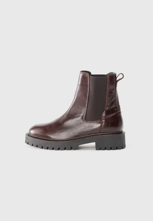 Mørkebrunt læder Chelsea-støvle med sort elastisk sidepanel og grov sort gummisål, set fra ydersiden.