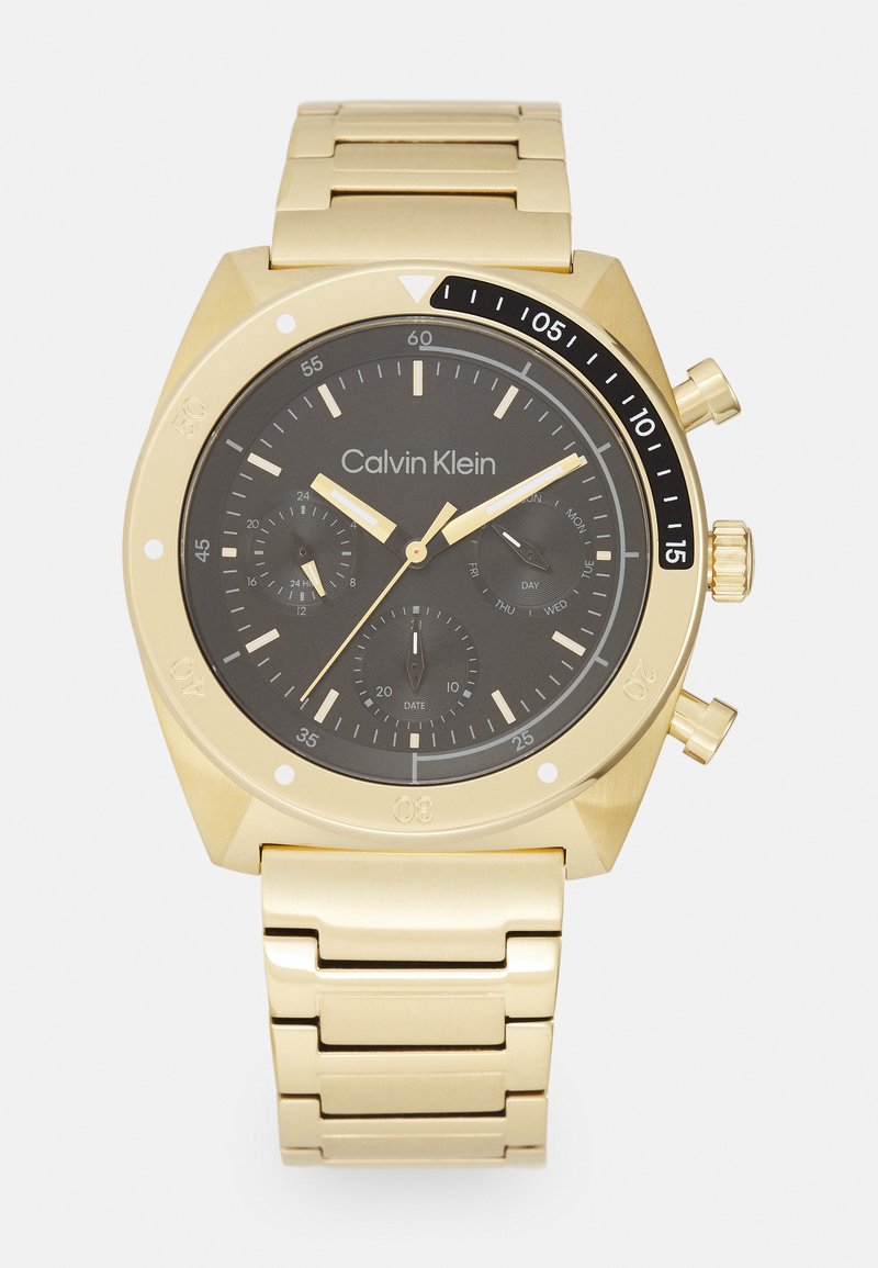 Gold metal chronograph watch with a black dial, featuring three sub-dials, luminous hands, and a link bracelet. Branding is on the dial.