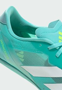 Light blue athletic shoe with a mesh upper, featuring a textured design, white accents, and the word "DISTANCESTAR" in green on the side.
