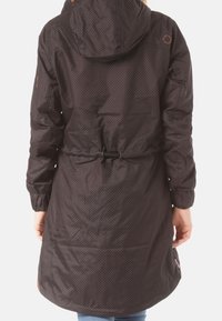 Svart, vattentät jacka med huva, insvängd midja och prickigt mönster. Har elastiska ärmslut och fickor på sidorna.