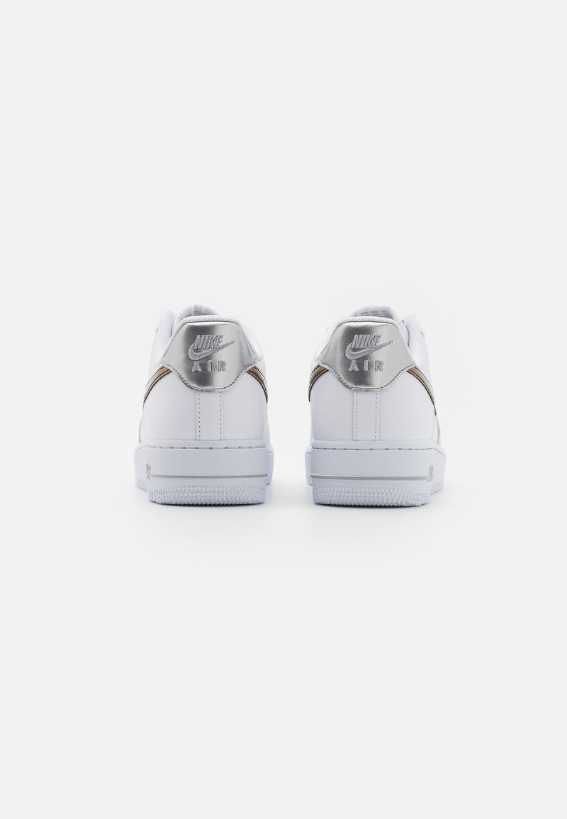 Sneakers bianchi in pelle con una superficie liscia, dettagli argentati sul tallone e il marchio "Nike Air" sul retro. Design classico a basse.