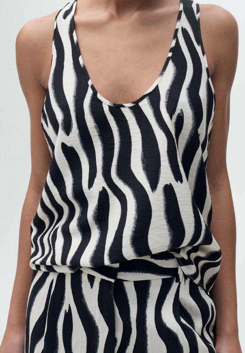 Zwart-wit mouwloze top met een zebra-strikpatroon, gemaakt van een gladde, lichte stof met een diepe halslijn en een losse pasvorm.