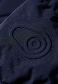 Tejido azul marino con un patrón circular en relieve. El material parece suave con un ligero brillo, resaltando los detalles del diseño.