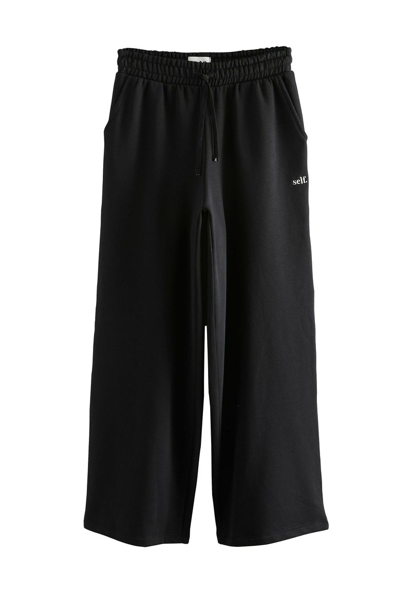 Sorte, brede sweatpants med elastisk talje, snor og sidelommer; har lille hvid "self." logo på fronten.