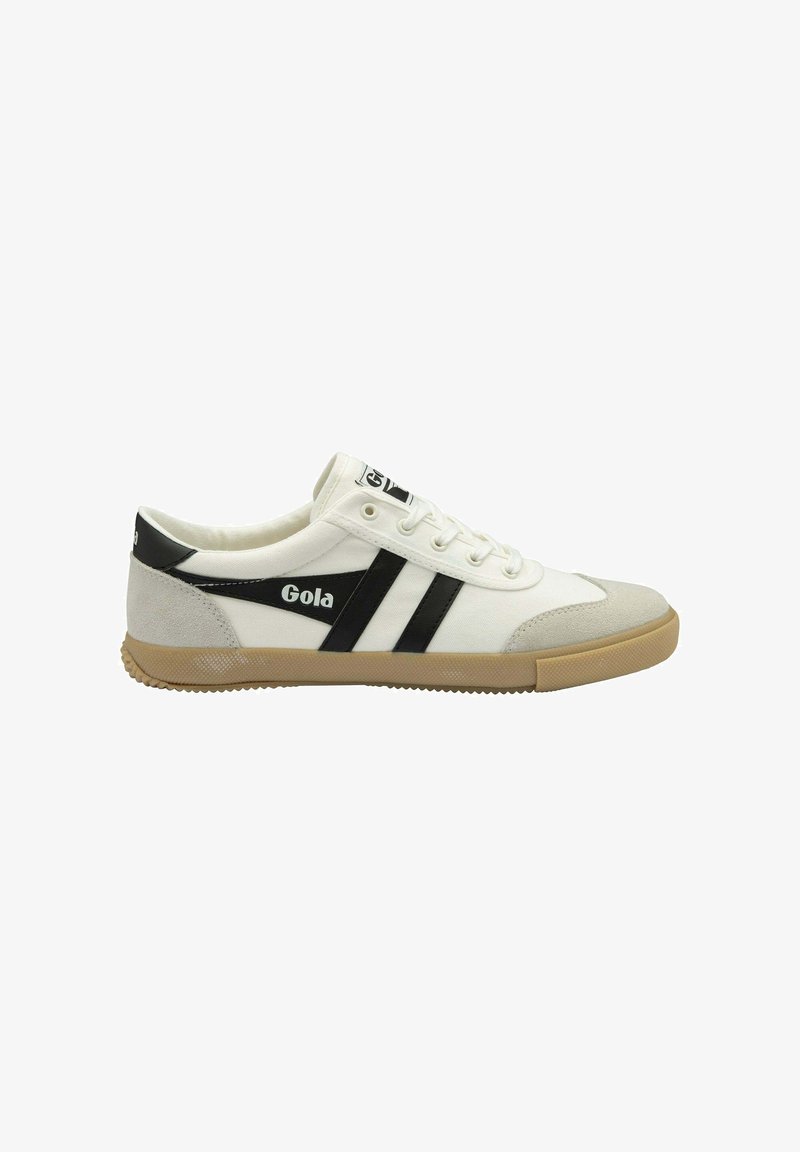 Baskets en toile blanches avec des bandes latérales noires et un logo, capuchon en suède gris, et semelle en caoutchouc couleur gomme. Comprend six œillets avec des lacets blancs.