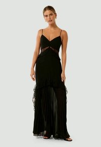 Black tiered dress featuring a fitted bodice, lace accents, spaghetti straps, and a pleated lower section with a ruffled hem.