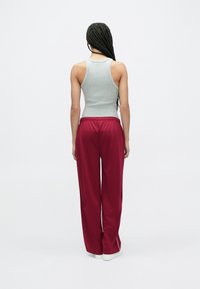 Pilka ribuota tankų palaidinė ir burgundiškos plačios kelnės su baltu šoniniu dryžiu. Minkštas audinys, laisvas kirpimas ir elastinė juosmens juosta.