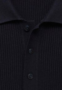 Ribbed black cardigan with a polo collar, featuring three black buttons and a textured fabric. Close-up view of design details.