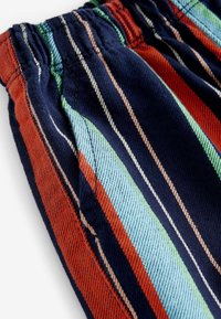 Tessuto a righe con uno sfondo blu navy e strisce rosse, verdi e azzurro chiaro. Vita elastica e texture tessuta.