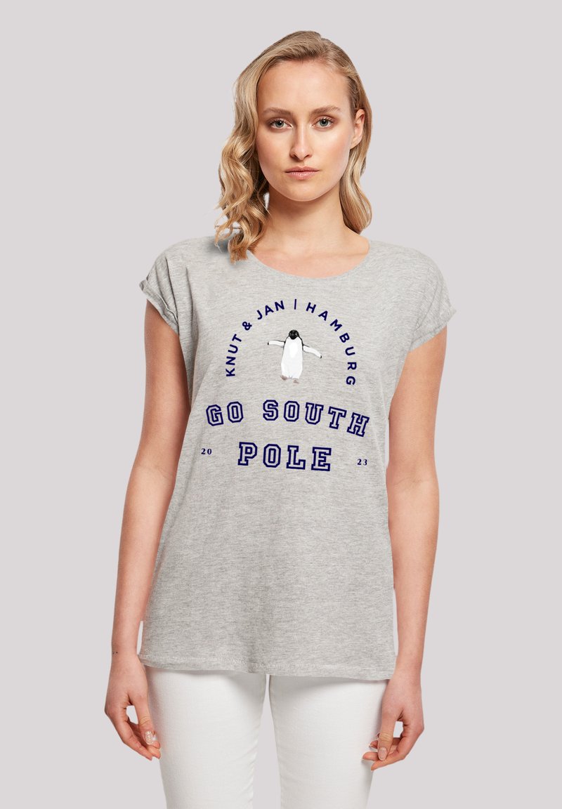 Graues T-Shirt mit kurzen Ärmeln, das ein Pinguin-Design und den Text "GEHE ZUR SÜDPOL" in Blau zeigt. Weicher Stoff mit lockerer Passform.