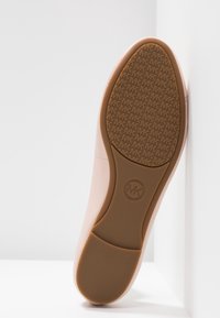 Chaussure rose clair avec une semelle en caoutchouc. La semelle présente un motif de prise texturé avec le logo "MK". Tige lisse sans coutures visibles.