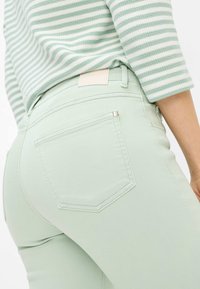 Jeans verde menta chiaro con design aderente e tasche frontali e posteriori. Presentano un'etichetta in vita e dettagli di cucitura discreti.