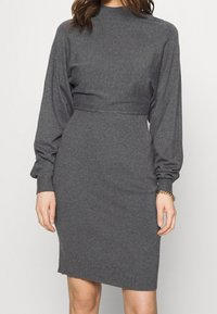 Graues, geripptes Kleid mit hohem Kragen, langen Ballonärmel und taillierter Passform. Weiches Strickmaterial, knielanges Design und subtile Textur.