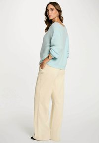 Maglione azzurro chiaro morbido con vestibilità rilassata e orlo a coste, abbinato a pantaloni in corda color crema a gamba larga con strisce verticali.