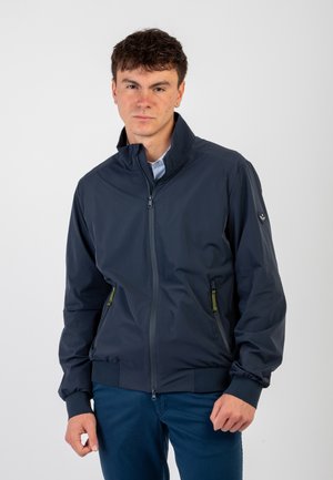 Giacca bomber blu navy con chiusura con zip, colletto alto, due tasche laterali e polsini e vita elasticizzati. Tessuto liscio con texture minima.
