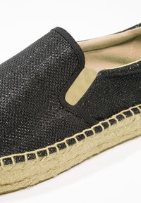 Espadrille noire à enfiler avec une tige texturée, ornée d'accents scintillants et d'une semelle en jute tressé pour plus de détails.
