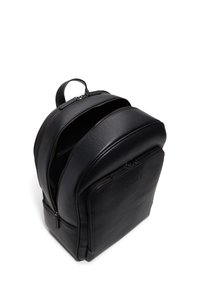 Zaino in pelle nera con forma arrotondata, due scomparti con zip, manico superiore e logo impresso in modo sottile sul davanti.