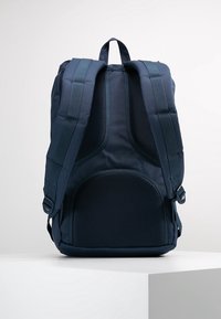 Granatowy plecak z wyściełanym siateczkowym tyłem, regulowanymi paskami i zamykaną kieszenią. Wykonany z trwałego materiału z wzmocnionymi szwami.