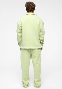Lichtgroene, oversized sweatshirt met een omgevouwen kraag en manchet-mouwen, gecombineerd met bijpassende toelopende sweatpants. Zachte stof textuur.