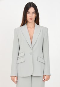 Blazer grigio chiaro con spalle imbottite, rever a punta, chiusura con un bottone e due tasche frontali angolari. Tessuto liscio e sartoriale.