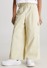 Ljusgula byxor med vida ben i ett mjukt tyg, med elastisk midja, två sidofickor och en cargo-ficka.