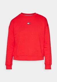 Sweat-shirt rouge à manches longues avec col rond, poignets et ourlet côtelés, petit logo rectangulaire "Tommy Jeans" centré sur la poitrine.