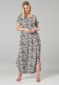 Maxikleid in hellem Beige mit schwarzen Zebra-Streifen, kurzen Ärmeln, V-Ausschnitt und Seitenschlitz, aus einem glatten, fließenden Stoff gefertigt.