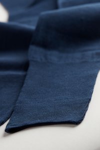 Tela azul marino con una textura suave, que presenta un borde limpio y plegado, además de un sutil patrón de punto. El material cae de manera suelta.