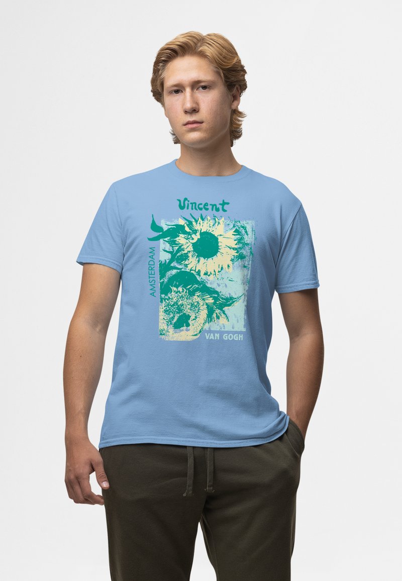 Camiseta de algodón azul claro con un estampado gráfico de girasoles, texto "Vincent" y "Amsterdam VAN GOGH" con acentos verdes.