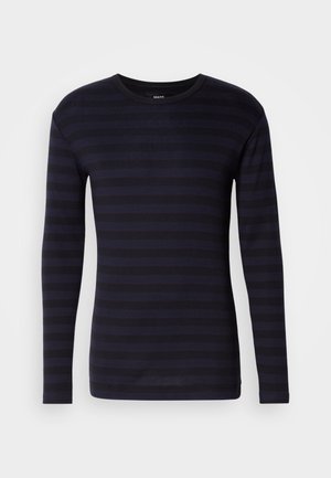 Mornarska majica dugih rukava s horizontalnim tamnim prugastim uzorkom i okruglim izrezom. Izrađena od mekog materijala s glatkom teksturom.