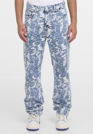 Blå og hvide acid-wash jeans båret med hvide sneakers, vist forfra fra talje til fødder.