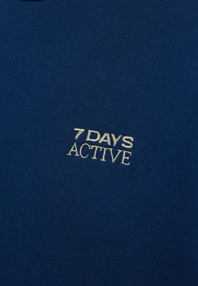 Tengerészkék, puha pamut póló. Elöl egy kicsi, krémszínű hímzett logó található: "7 DAYS ACTIVE".