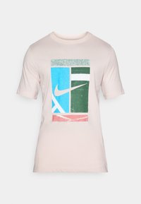 Svetlo roza majica s tiskom, ki vključuje modre, zelene, bele in roza pravokotnike, vključno z logotipom Nike na modrem delu.