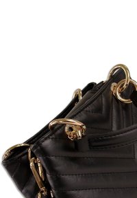 Sac à main en cuir noir avec un motif matelassé, des accessoires dorés et de grands anneaux fixés sur les côtés. Texture lisse et forme structurée.