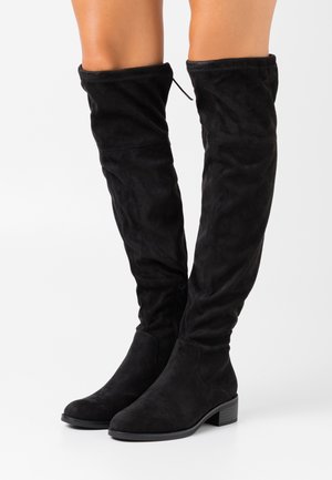 Sorte over-knee støvler lavet af ruskind, med en slank form, lav hæl i stablede lag og en sidelukning for nem påklædning. Glat tekstur hele vejen rundt.