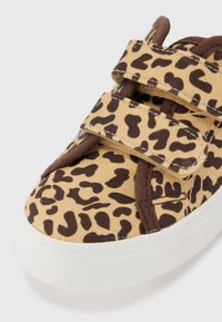 Leopard print sneaker featuring a canvas upper with brown accents, white rubber sole, and adjustable Velcro straps.